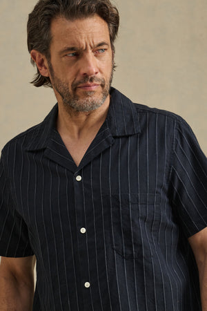 A man with short brown hair and a beard wears the GUNNER SHIRT by Velvet by Graham & Spencer, looking to the side against a neutral background.