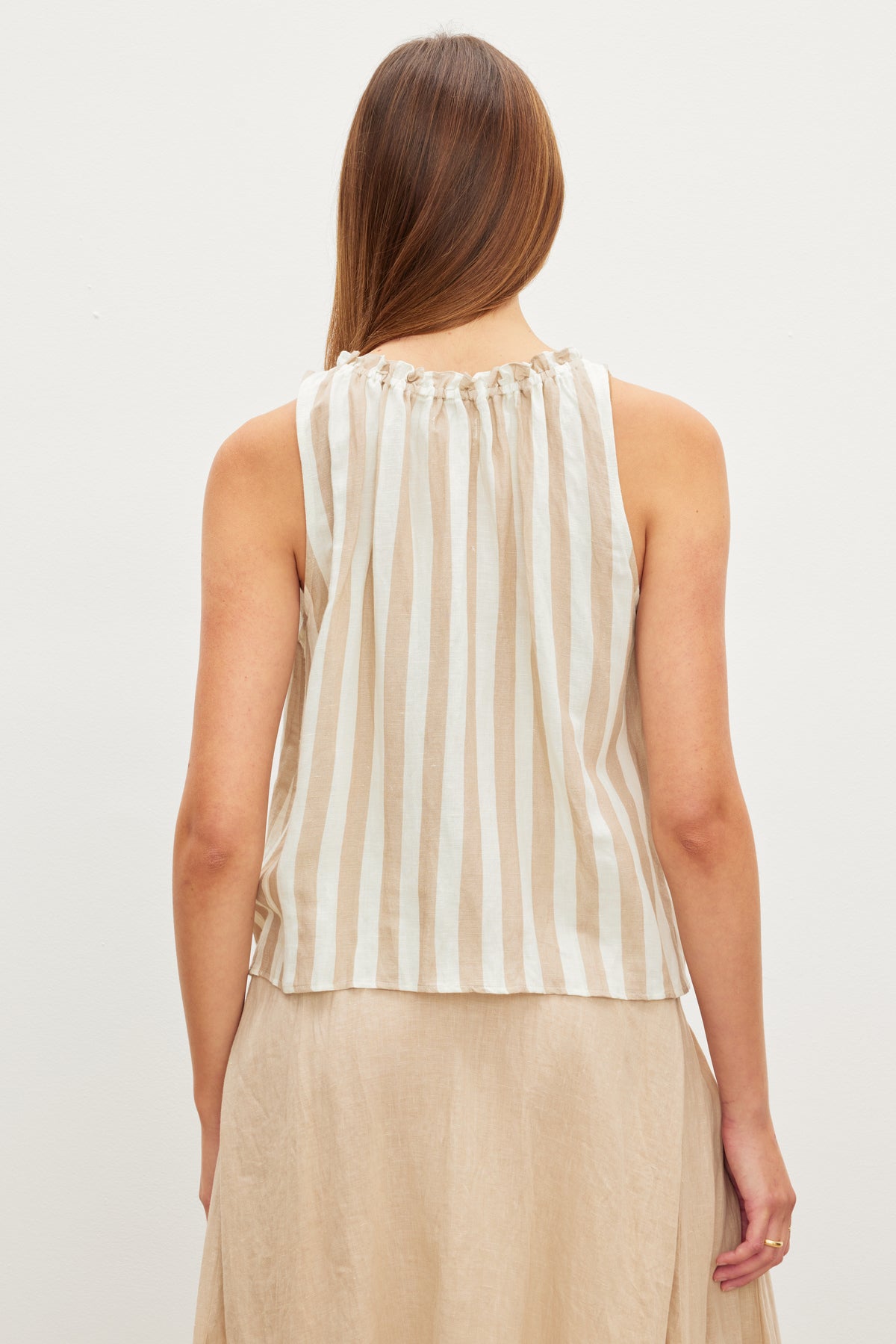   Woman from behind wearing a Velvet by Graham & Spencer ERICA STRIPED LINEN TANK TOP and a beige skirt. 