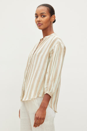 Person in a GABBY STRIPED LINEN TOP by Velvet by Graham & Spencer and light pants standing against a plain background.