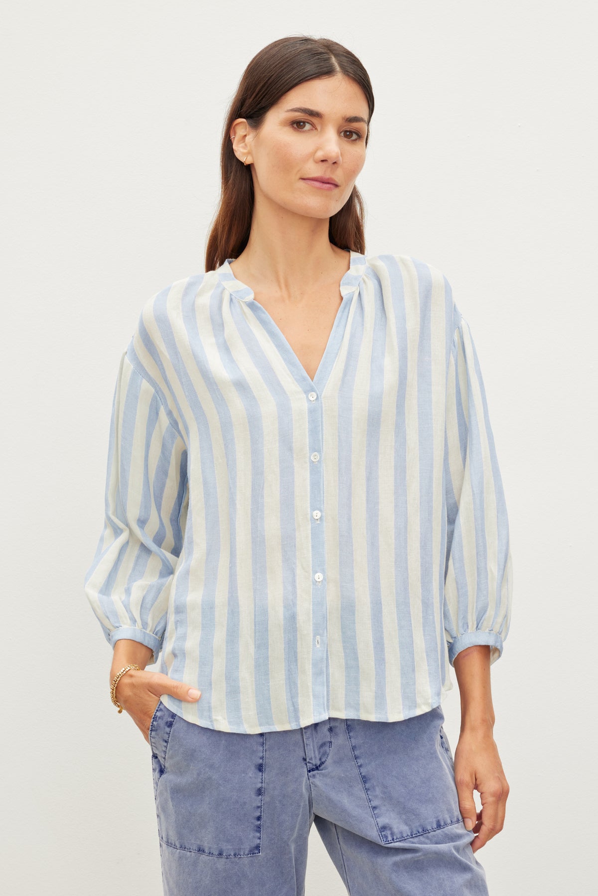   Woman in a Velvet by Graham & Spencer Gabby Striped Linen Top and blue jeans standing against a white background. 