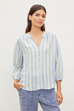 Woman in a Velvet by Graham & Spencer Gabby Striped Linen Top and blue jeans standing against a white background.