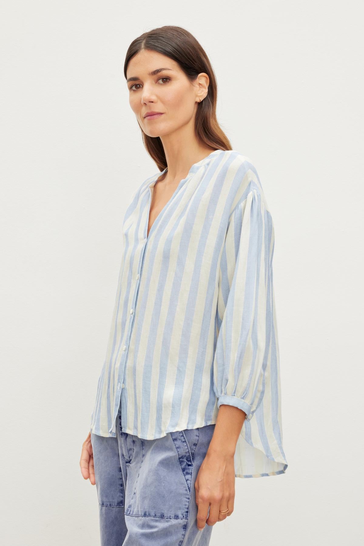   Woman in a GABBY STRIPED LINEN TOP by Velvet by Graham & Spencer and jeans, standing against a plain white background. 