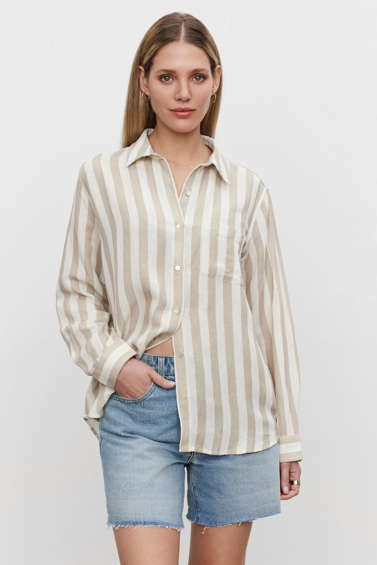 The model is wearing a HARLOW STRIPED LINEN BUTTON-UP SHIRT by Velvet by Graham & Spencer and denim shorts.-36247888101569