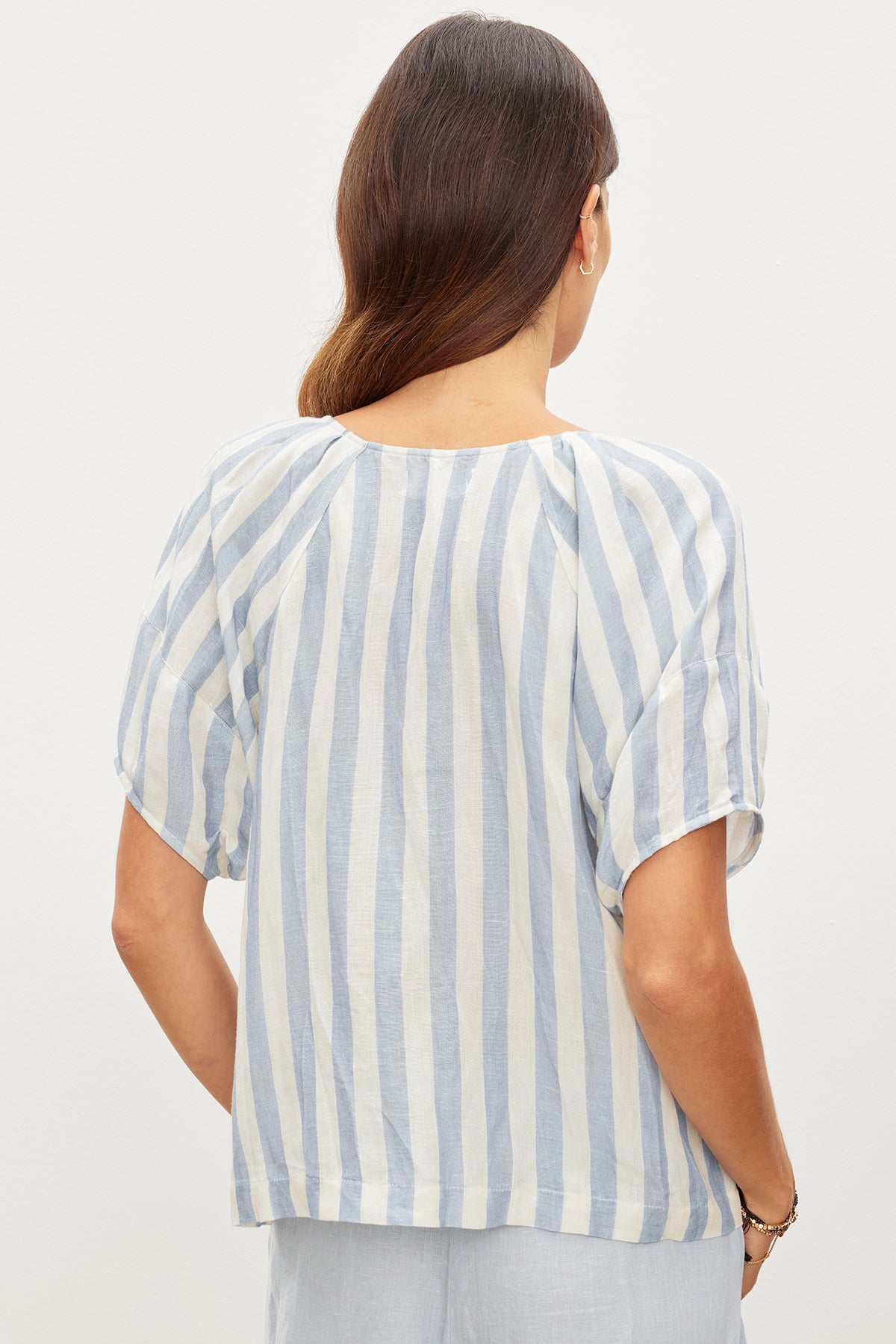   The back view of a woman wearing a Velvet by Graham & Spencer KATY STRIPED LINEN TOP with West Coast vibes. 