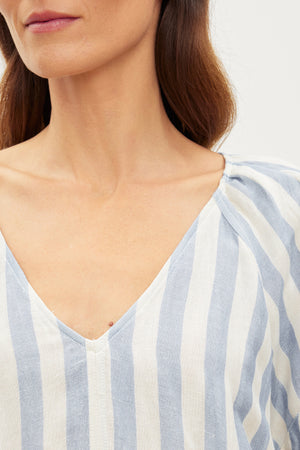A woman wearing a Velvet by Graham & Spencer KATY STRIPED LINEN TOP exudes West Coast vibes.