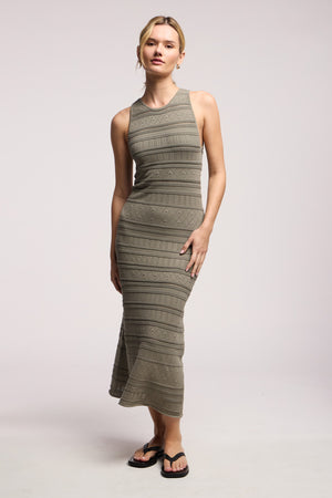 A woman stands in a studio wearing the YLENA DRESS by Velvet by Graham & Spencer, featuring stripes, pointelle details, an A-line hem, and black flip-flops.