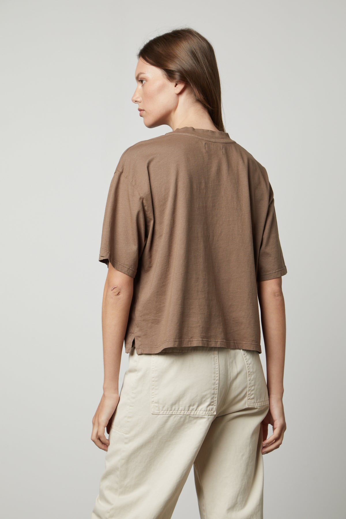  The back view of a woman styling a CLARAH CREW NECK TEE from Velvet by Graham & Spencer, an oversized fit brown cropped t-shirt in sueded jersey fabric. 