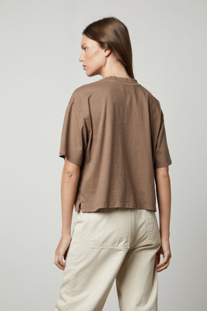 The back view of a woman styling a CLARAH CREW NECK TEE from Velvet by Graham & Spencer, an oversized fit brown cropped t-shirt in sueded jersey fabric.