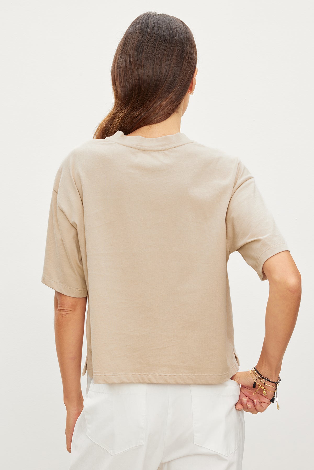   The relaxed back view of a woman wearing a beige CLARAH CREW NECK TEE by Velvet by Graham & Spencer featuring sueded jersey fabric. 