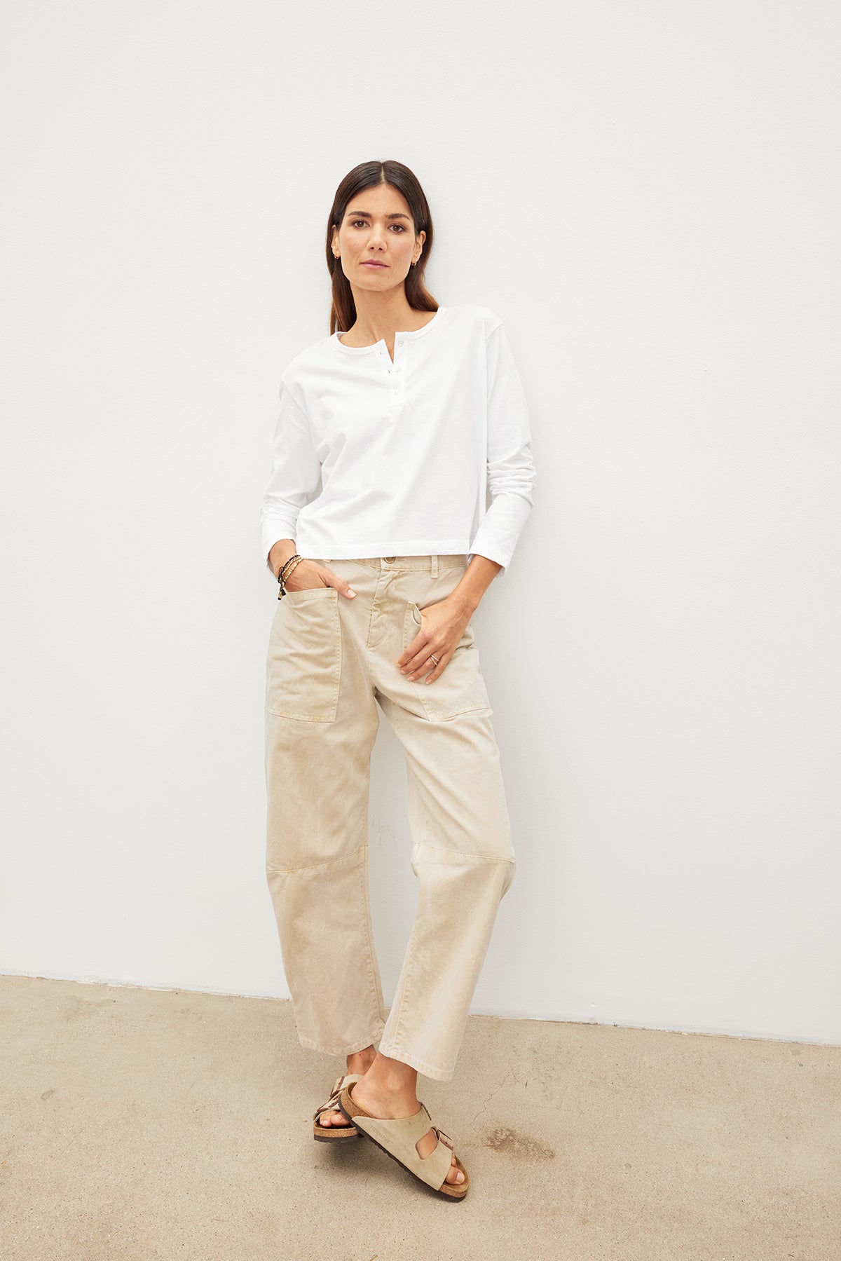   A woman wearing a DELIAH CROPPED HENLEY shirt by Velvet by Graham & Spencer and beige pants in her everyday wardrobe. 