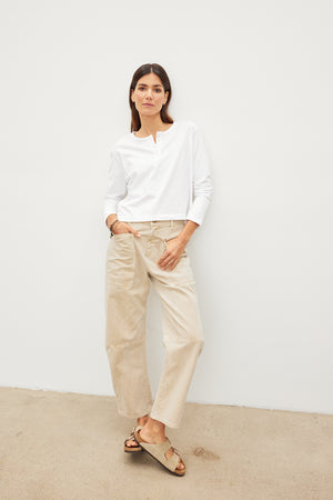 A woman wearing a DELIAH CROPPED HENLEY shirt by Velvet by Graham & Spencer and beige pants in her everyday wardrobe.