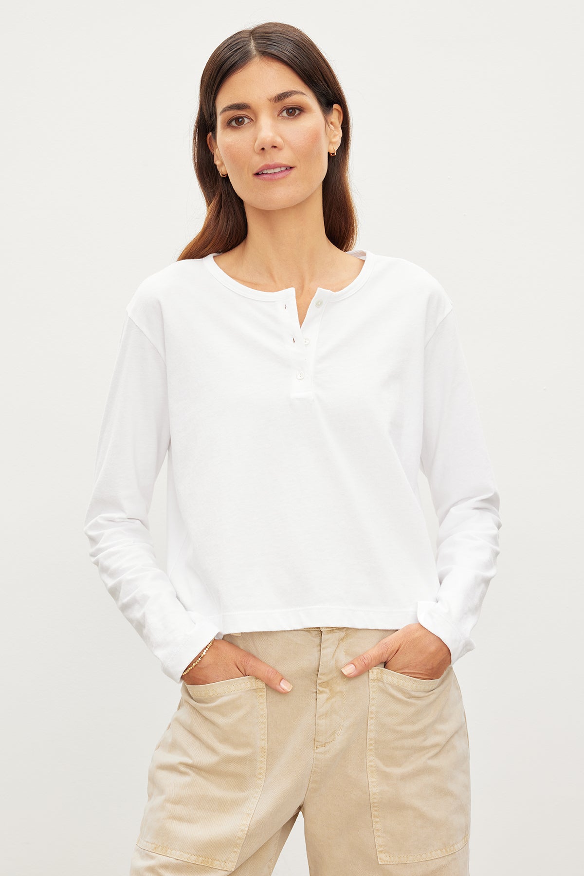   The model is wearing a white Deliah Cropped Henley tee and khaki pants. 