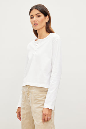 A woman in a white shirt sporting the Velvet by Graham & Spencer Deliah Cropped Henley, an everyday wardrobe look with a sueded jersey cotton fabric.