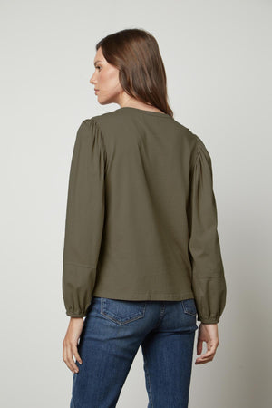The back view of a woman wearing jeans and a green blouse with a JETTY CREW NECK TEE by Velvet by Graham & Spencer.