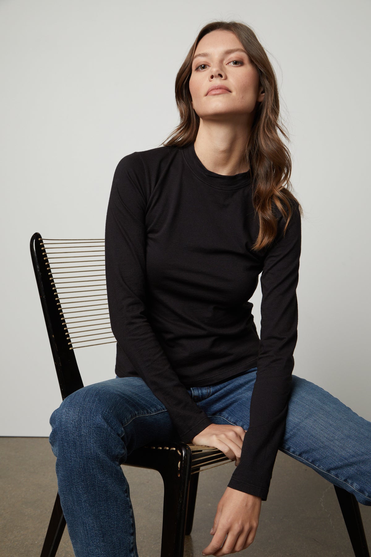 A woman wearing a black Velvet by Graham & Spencer LINNY MOCK NECK TEE and jeans.-26872369414337