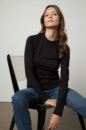 A woman wearing a black Velvet by Graham & Spencer LINNY MOCK NECK TEE and jeans.