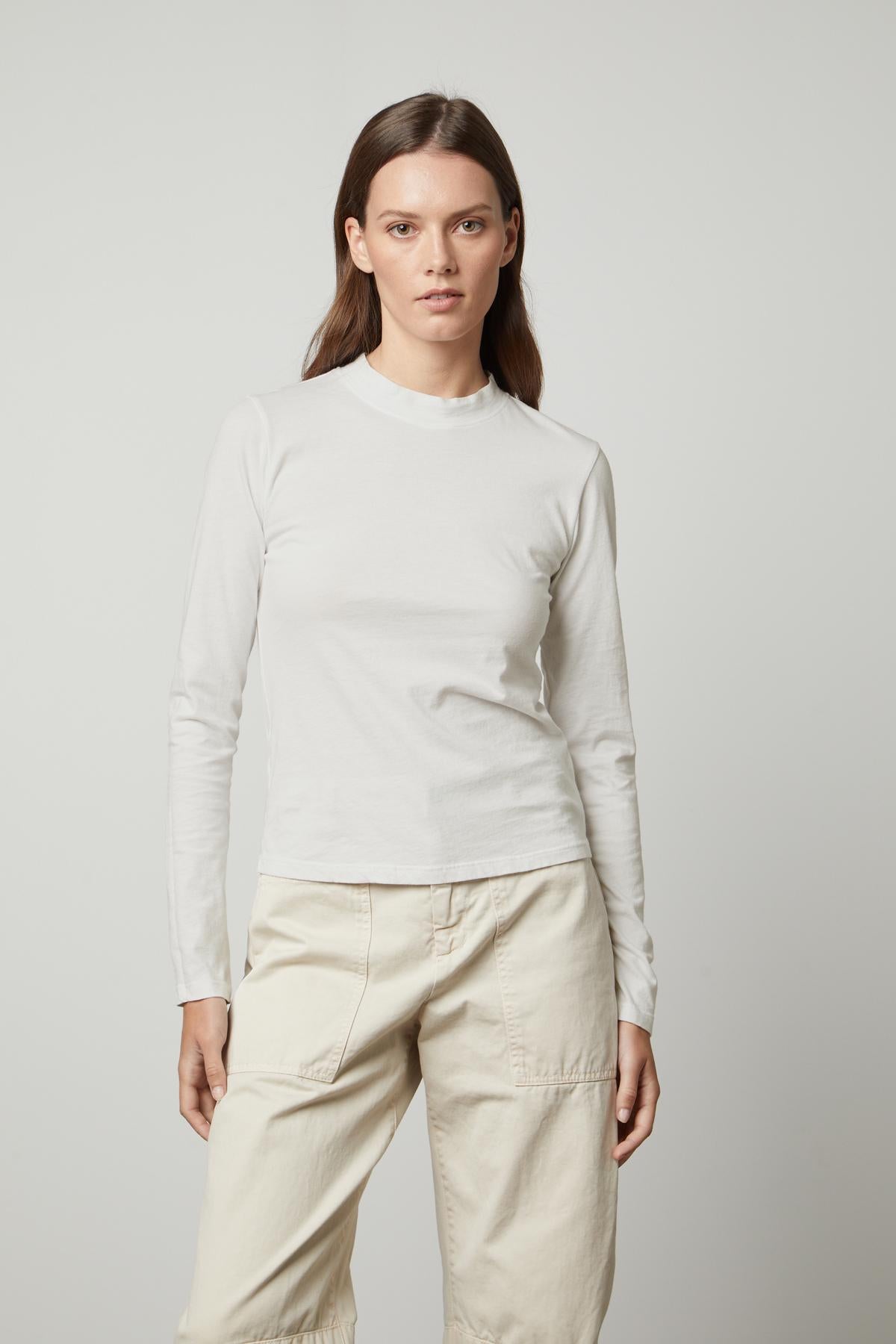   The model is wearing a white LINNY MOCK NECK TEE by Velvet by Graham & Spencer. 