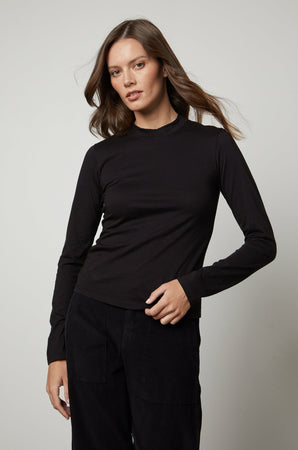 A woman wearing the Velvet by Graham & Spencer LINNY MOCK NECK TEE with a fitted silhouette.
