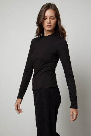 The model is wearing a LINNY MOCK NECK TEE by Velvet by Graham & Spencer.