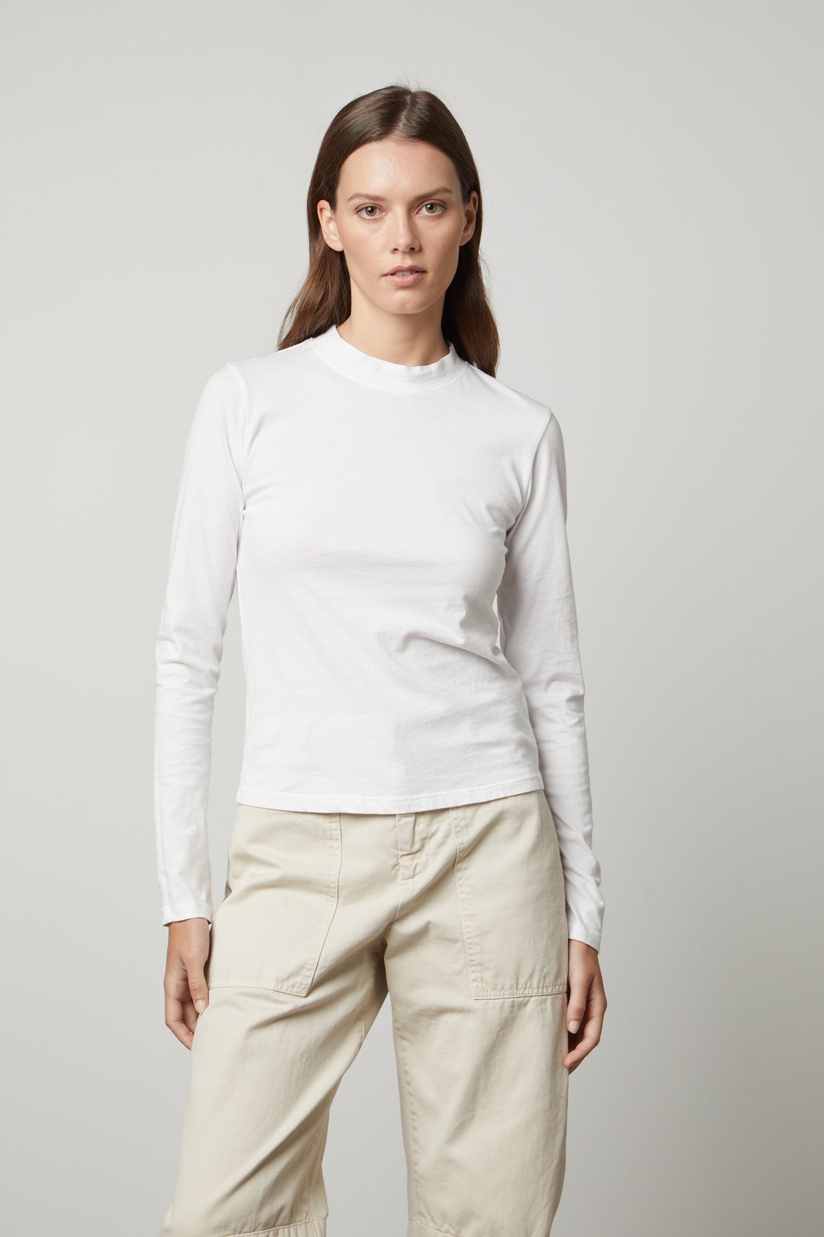 The LINNY MOCK NECK TEE by Velvet by Graham & Spencer is wearing a white long-sleeved tee.-35655933952193