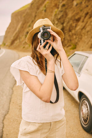 a woman taking a picture with her Velvet by Graham & Spencer REMI RUFFLE SLEEVE TOP on the side of the road.