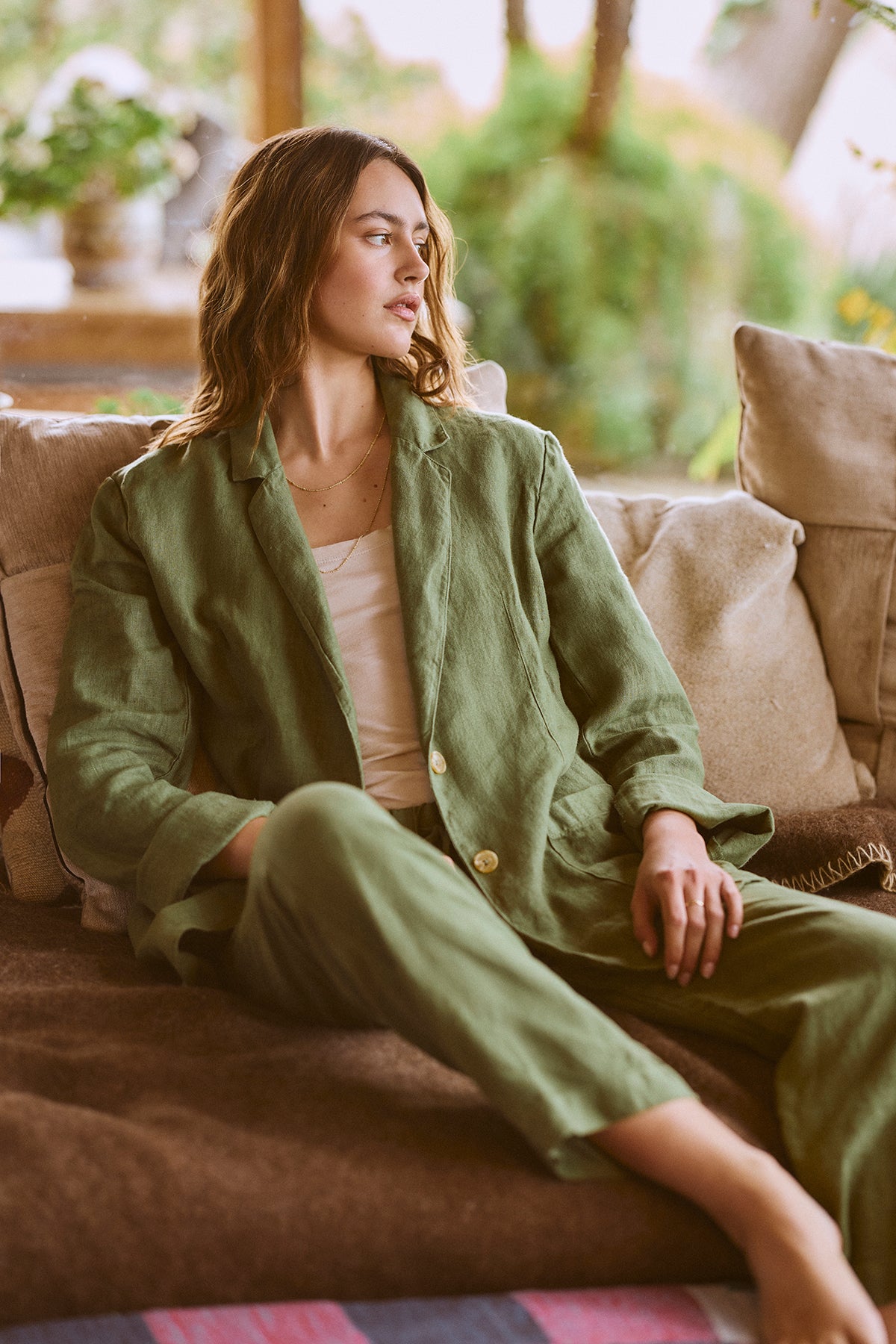 A woman is sitting on a couch in Velvet by Graham & Spencer's CINDY HEAVY LINEN PANT.-26671437447361