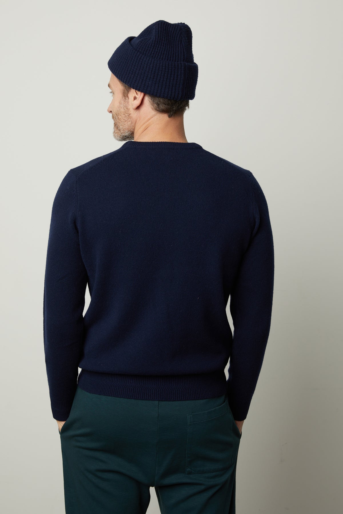   The back view of a man in a warm Velvet by Graham & Spencer DASHELL CREW NECK SWEATER and stylish green pants. 