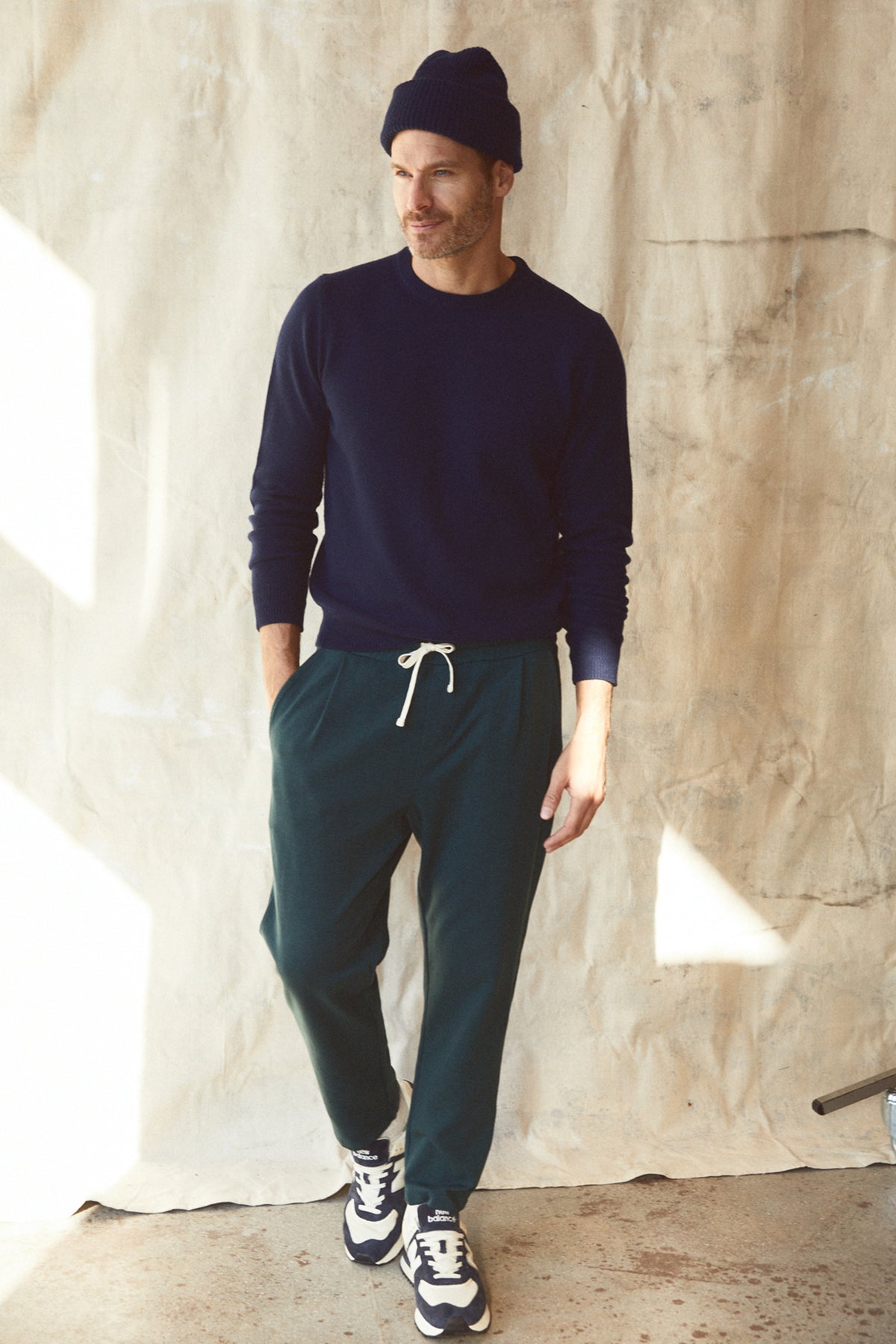 A man standing in front of a wall wearing a Velvet by Graham & Spencer PARKER sweatpant and sweater.-26846217765057
