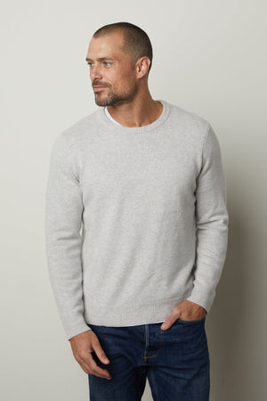 A refined man wearing a Velvet by Graham & Spencer DASHELL CREW NECK SWEATER and jeans exudes style and warmth.