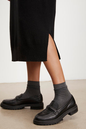 A woman wearing a cozy KADEN SWEATER DRESS by Velvet by Graham & Spencer with black loafers.