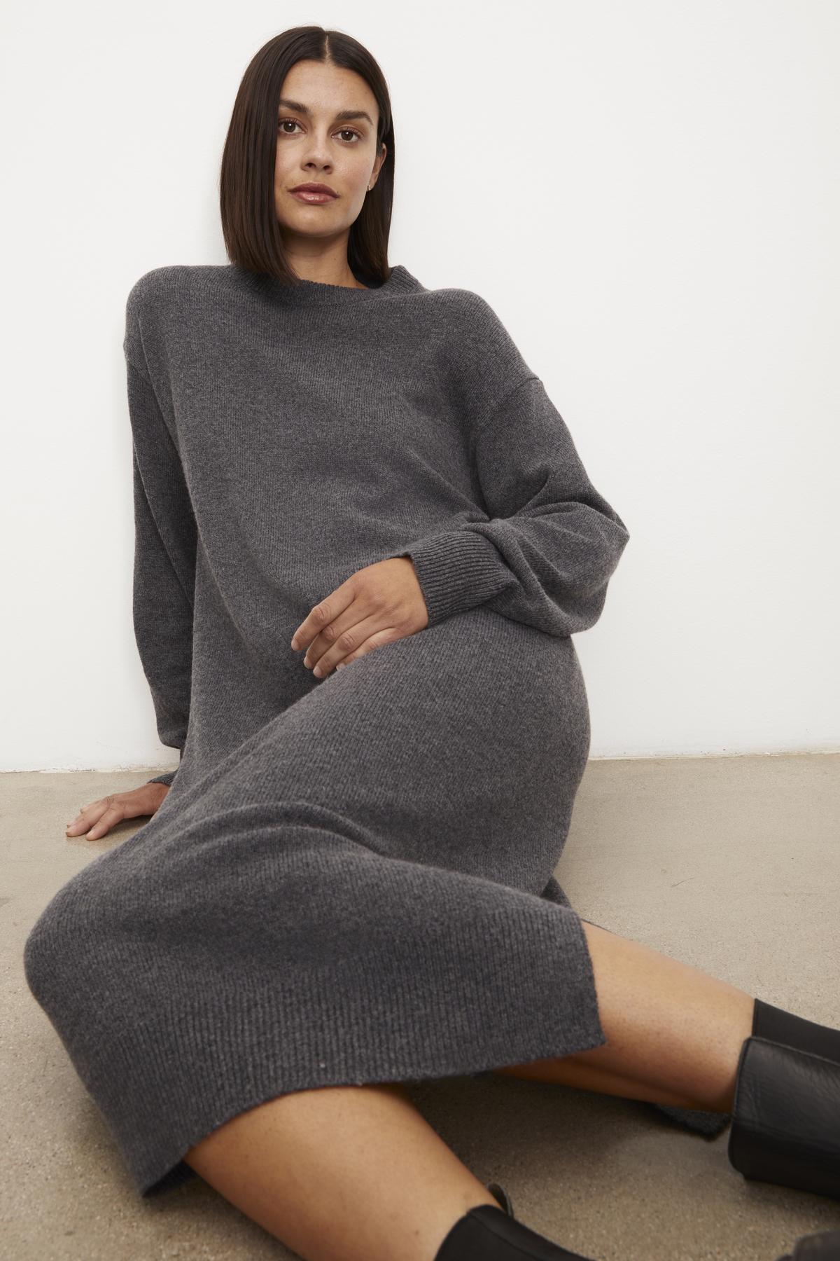 Woman in a gray Velvet by Graham & Spencer KADEN SWEATER DRESS with a crew neckline sitting against a white background, looking at the camera, with black boots on.-35655585333441