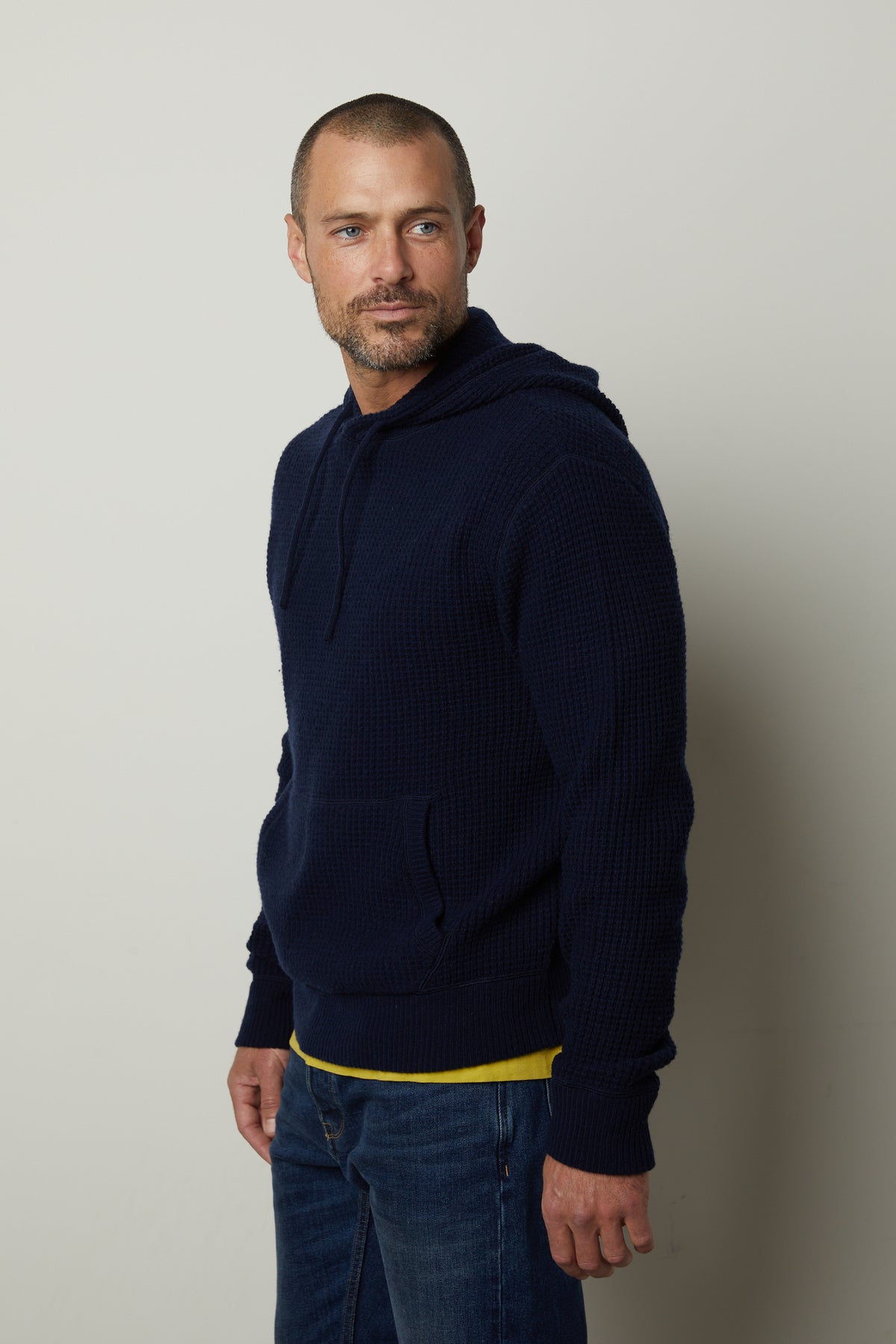   A man wearing a Velvet by Graham & Spencer Shane Sweater Hoodie and jeans. 