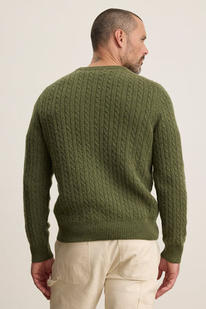 A man faces away from the camera, wearing the ALONZO SWEATER by Velvet by Graham & Spencer in olive green and light beige pants.