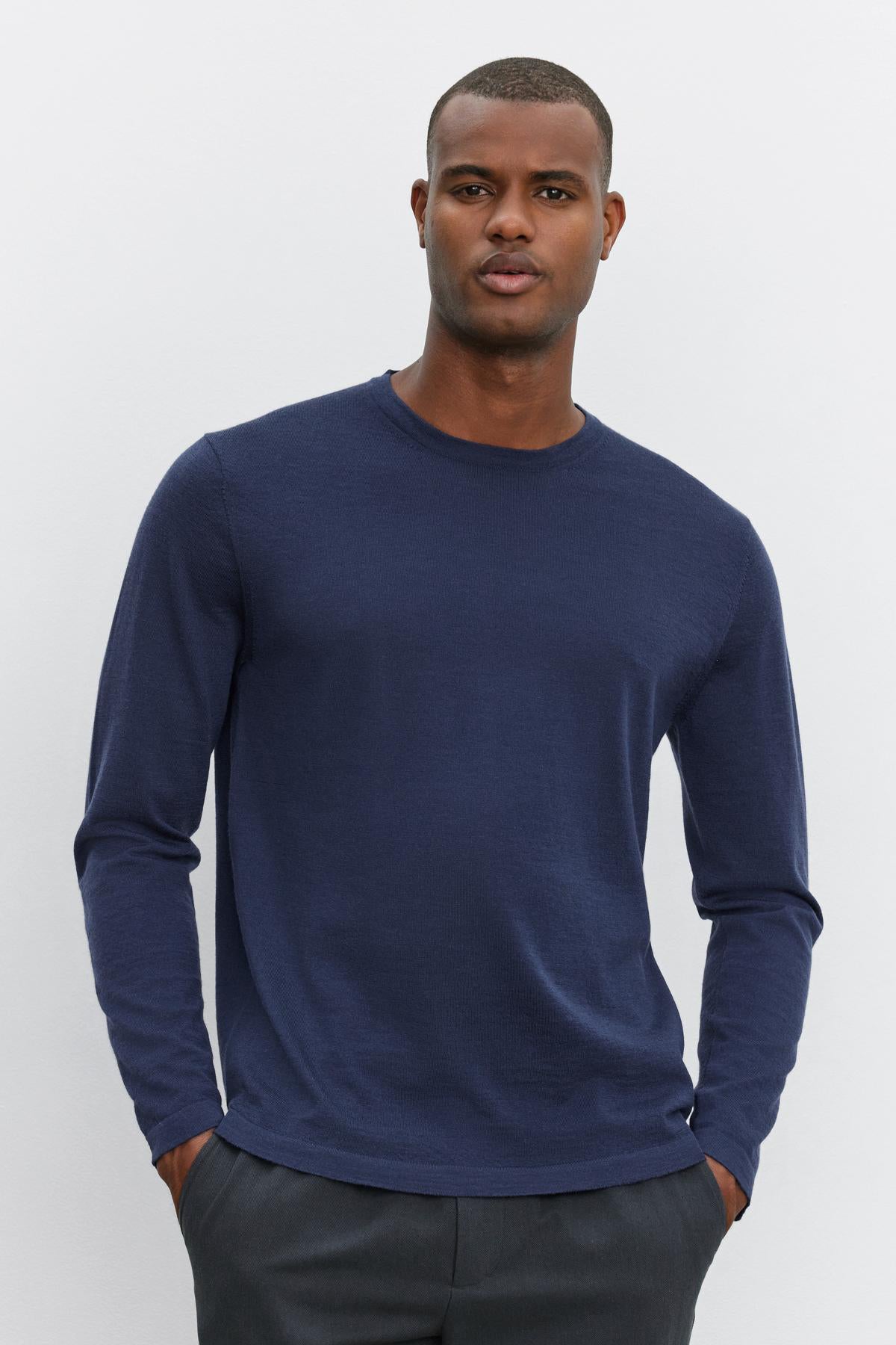   A person stands against a plain white background, wearing the ALVIN SWEATER by Velvet by Graham & Spencer and dark pants, with hands in pockets. 