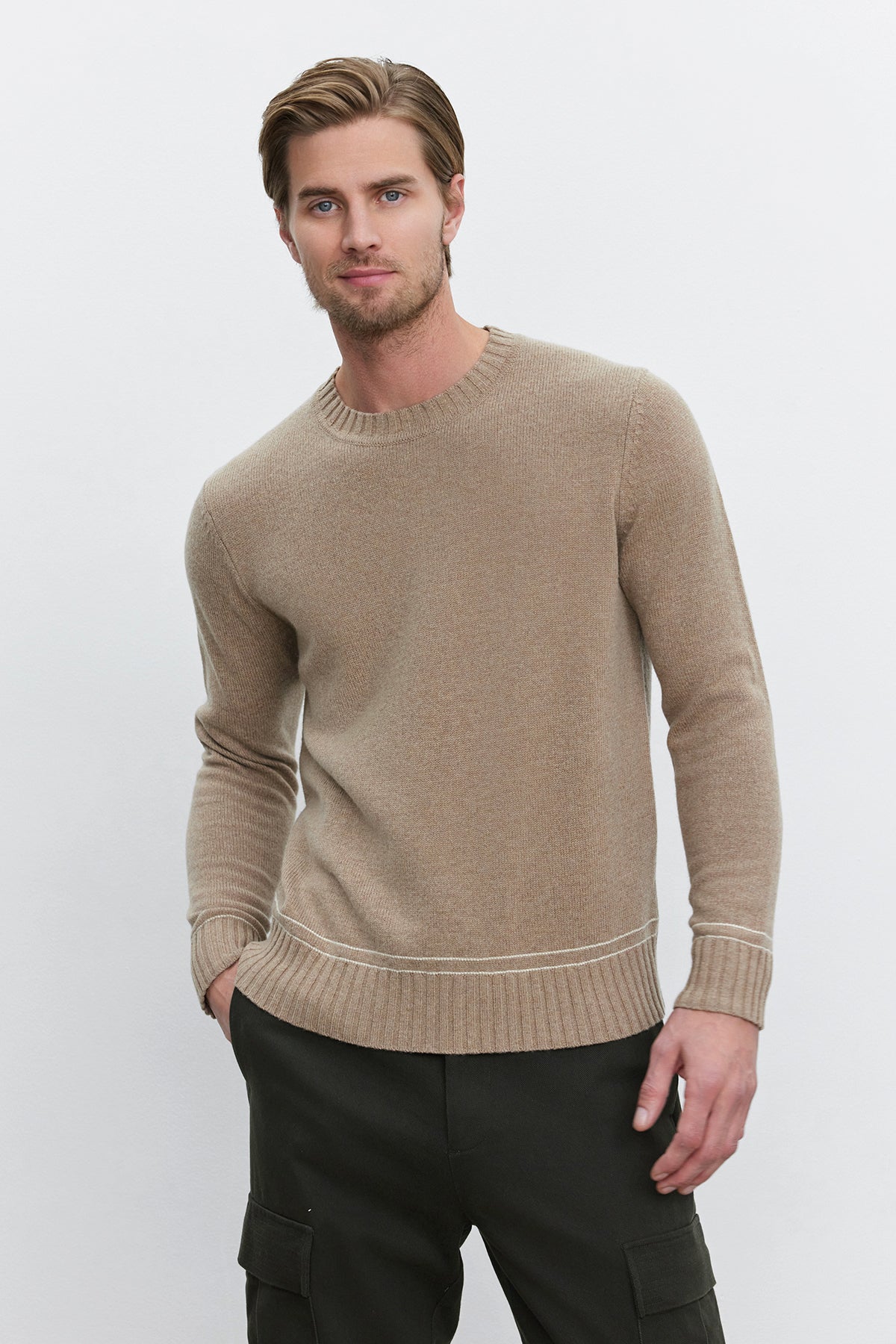   A man with short hair wearing the ATTICUS SWEATER by Velvet by Graham & Spencer and dark pants stands against a plain white background. 