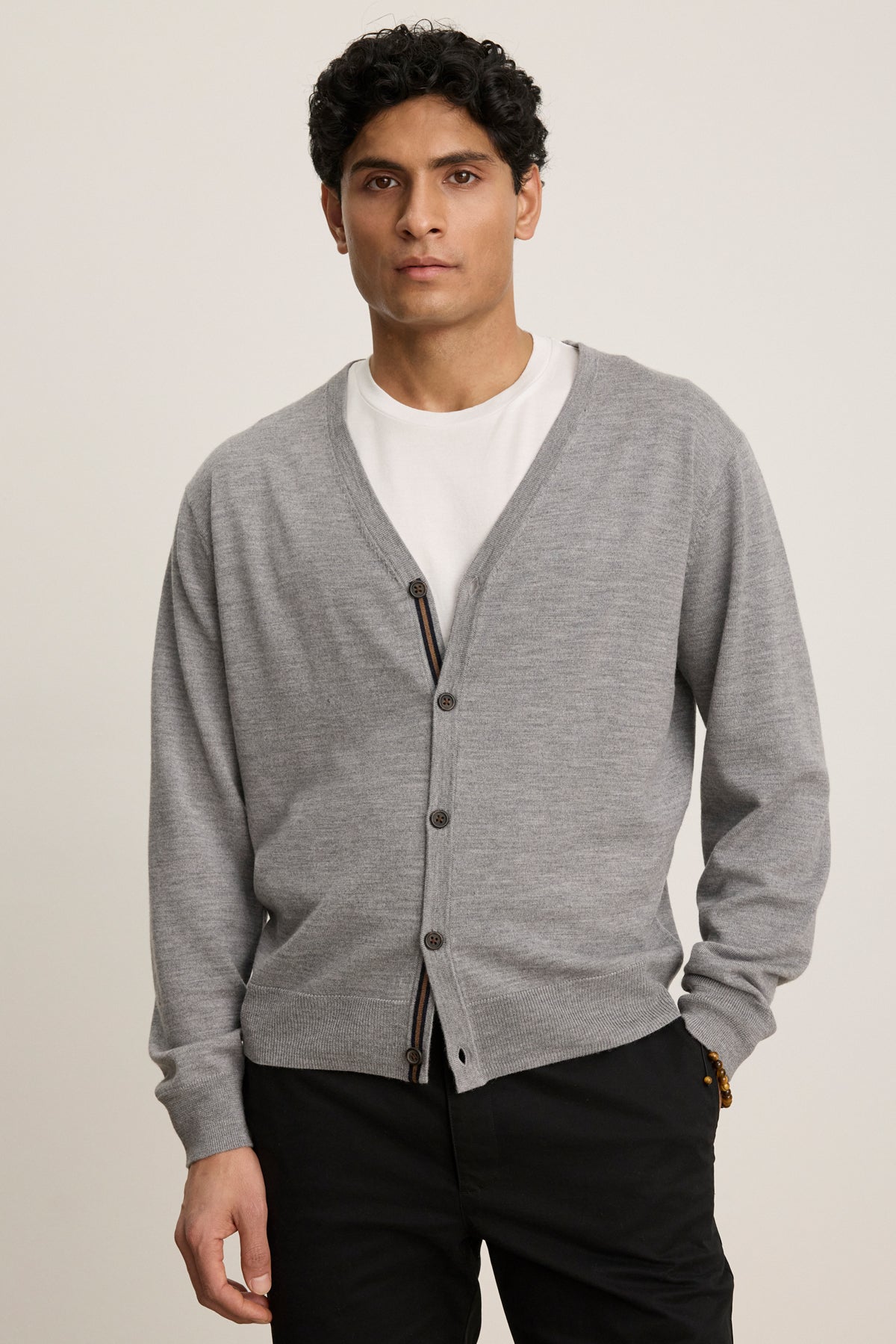 A man wears the SILVIO CARDIGAN by Velvet by Graham & Spencer over a white t-shirt and black pants, standing against a plain background.-39841095680193