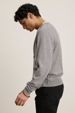 A person with short dark hair, wearing the SILVIO CARDIGAN by Velvet by Graham & Spencer and black pants, stands sideways against a plain light background.