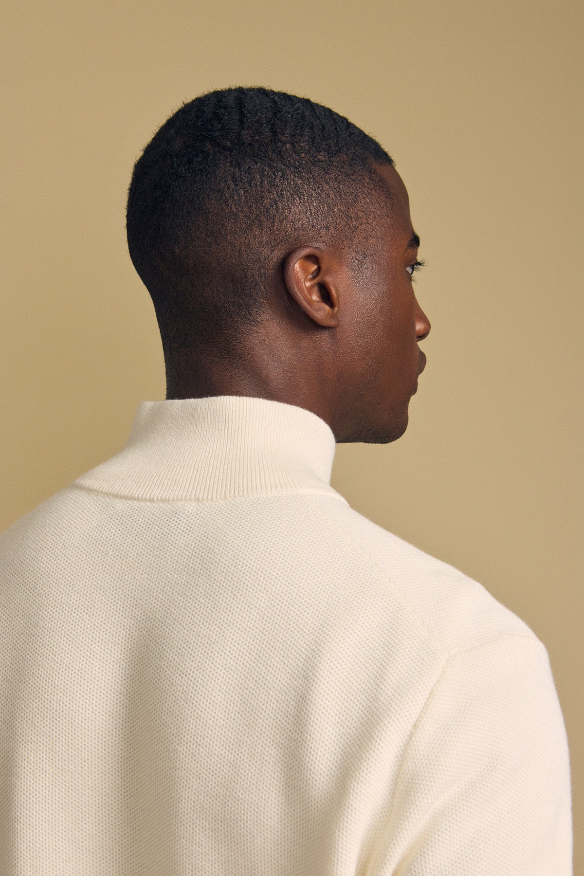 A man with short hair is shown from behind against a plain beige background, wearing the cream-colored BRENTWOOD SWEATER by Velvet by Graham & Spencer.-41859621060801