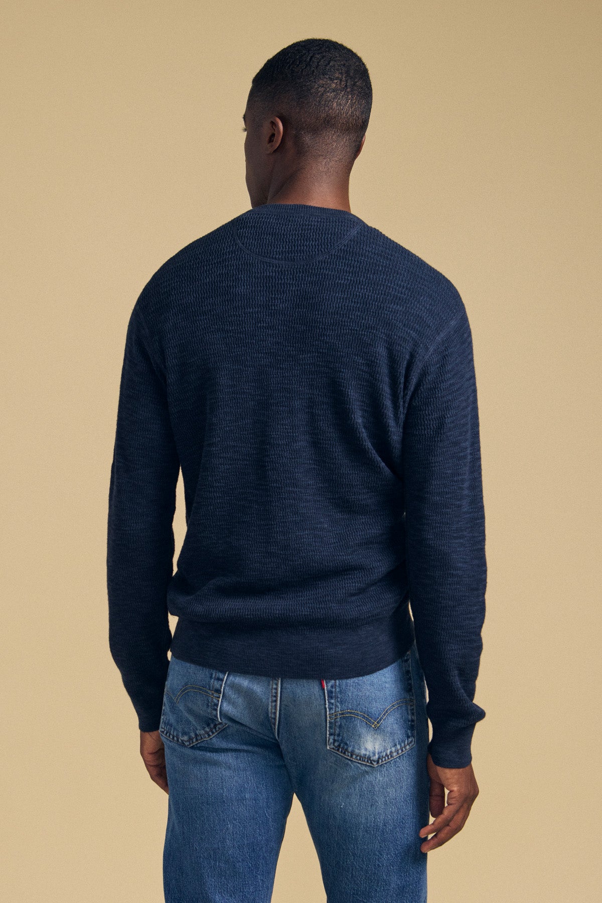 A person viewed from behind wearing a textured navy blue cotton linen blend CONOR SWEATER by Velvet by Graham & Spencer and blue jeans.