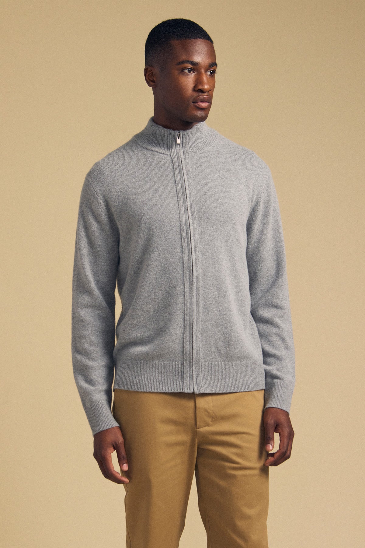 A man wearing a grey Velvet by Graham & Spencer DALLEN FULL-ZIP SWEATER and tan trousers.