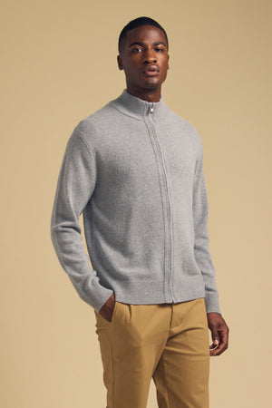 A man wears a gray, long-sleeved DALLEN FULL-ZIP SWEATER and tan trousers.
