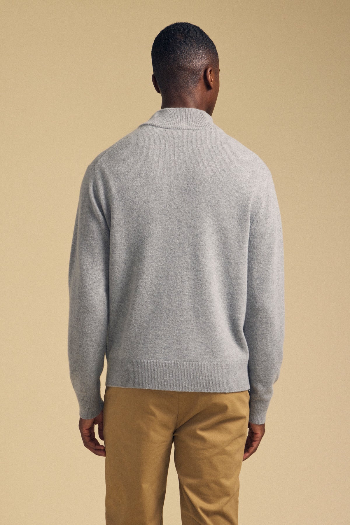 Back view of a person wearing a grey DALLEN FULL-ZIP SWEATER and tan trousers.