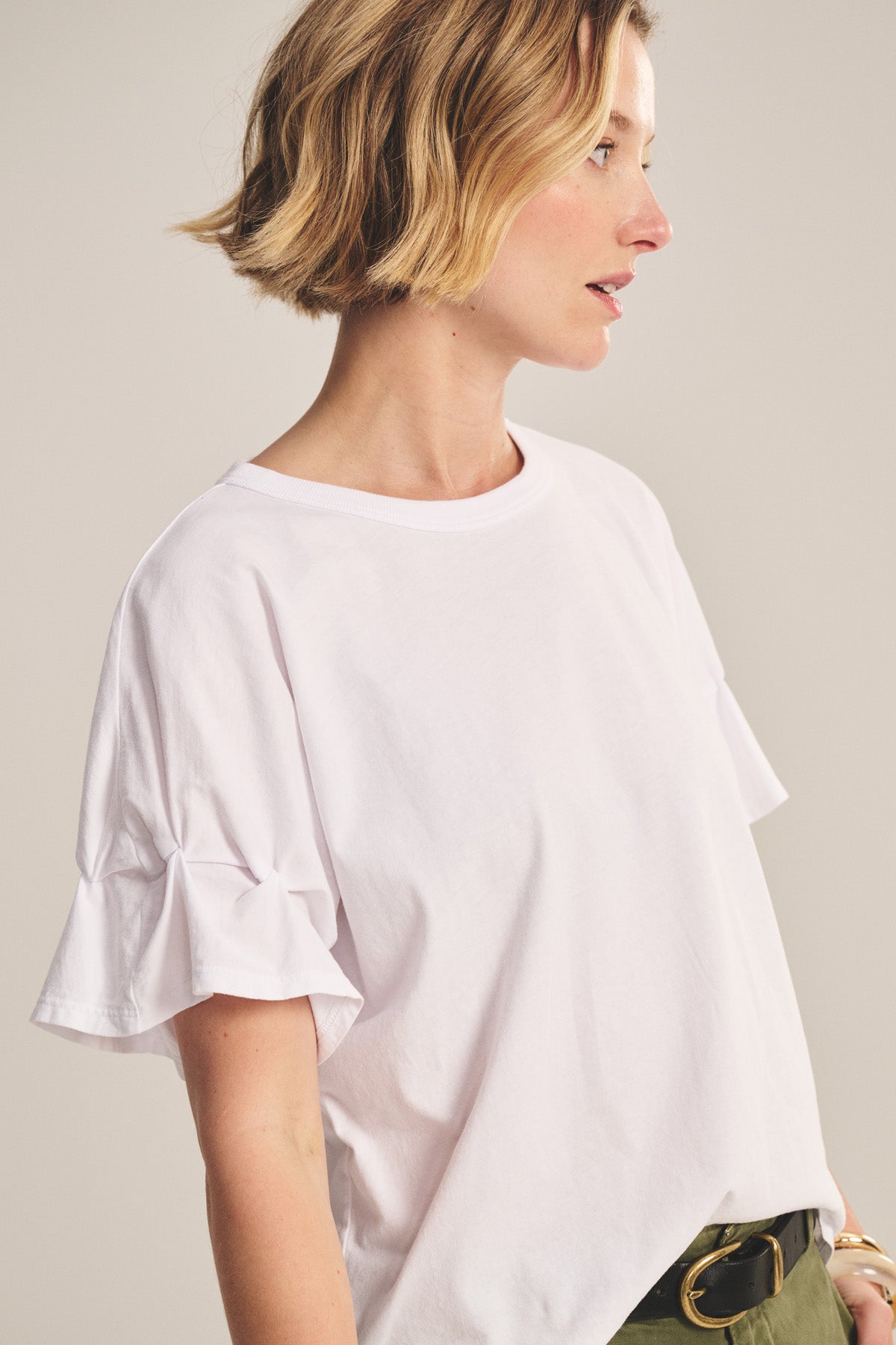 A woman with short blonde hair wears the TAE TEE by Velvet by Graham & Spencer and olive green pants, standing against a neutral background.-40808728690881