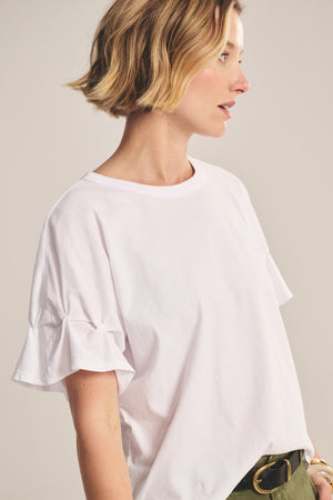A woman with short blonde hair wears the TAE TEE by Velvet by Graham & Spencer and olive green pants, standing against a neutral background.