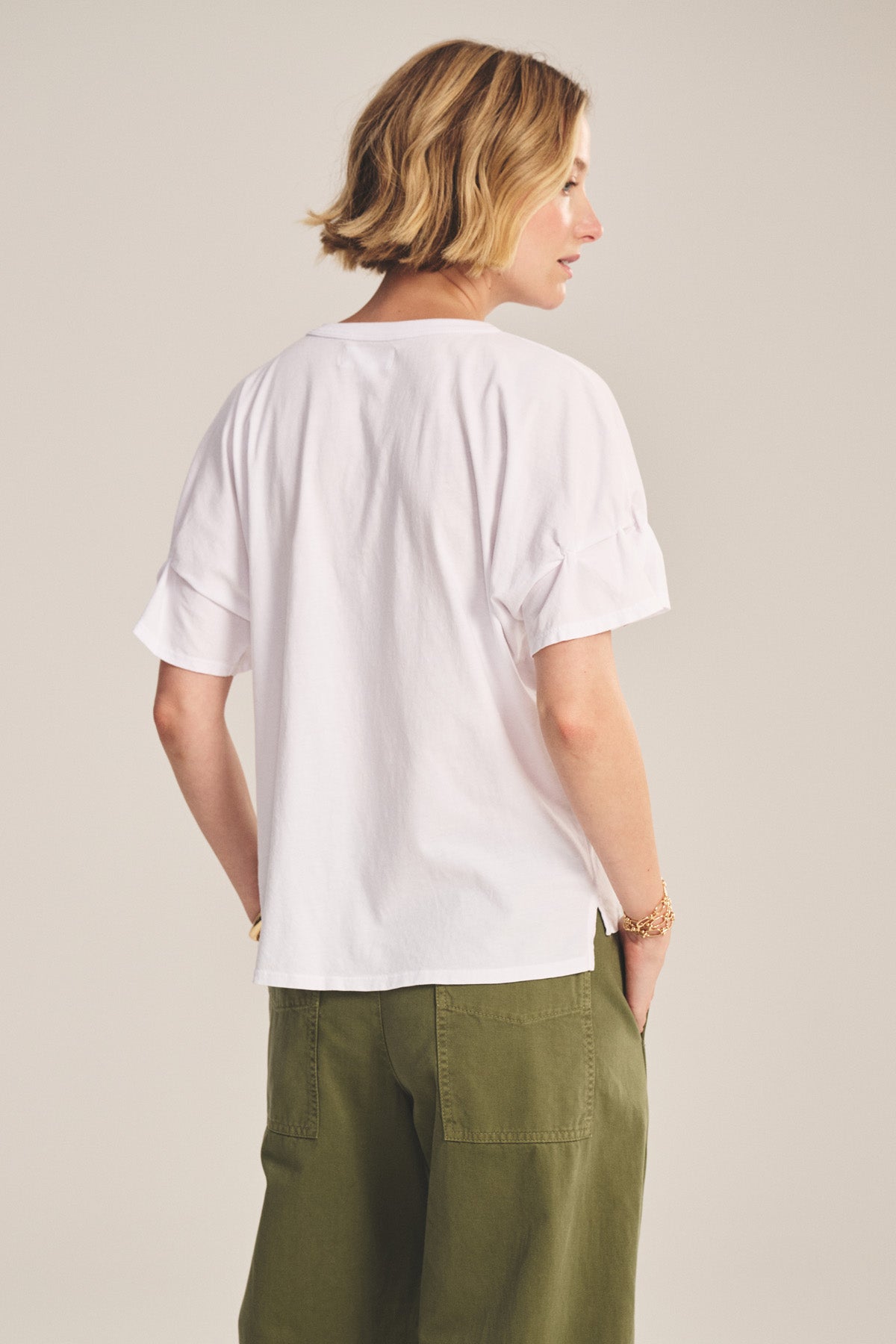 A person with short blonde hair is shown from behind, wearing the TAE TEE by Velvet by Graham & Spencer and olive green pants against a neutral background.-40808728658113