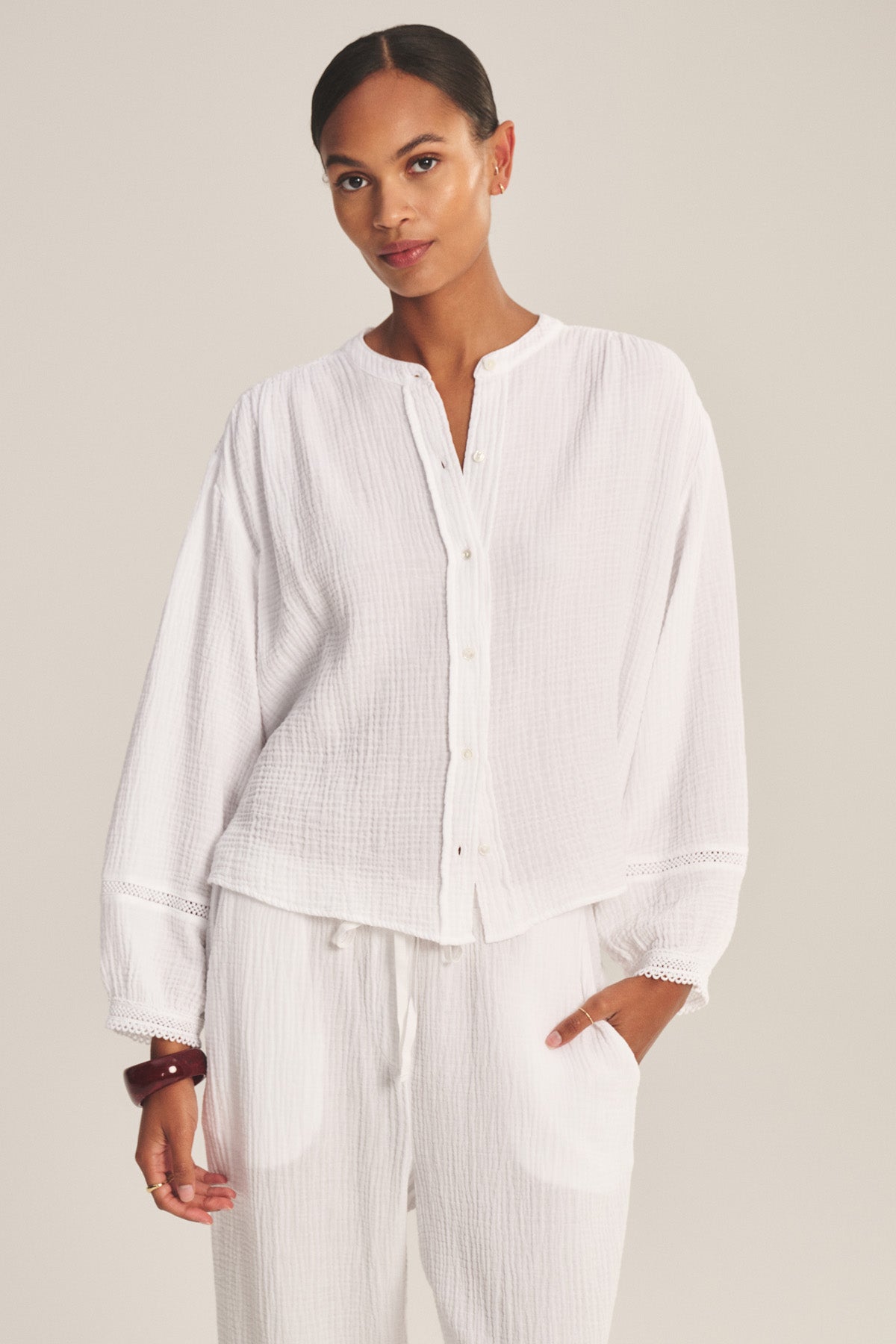 A woman wears the TARIA TOP by Velvet by Graham & Spencer with matching white drawstring pants, standing against a neutral background for an effortlessly lightweight, comfortable look.-41128866742465
