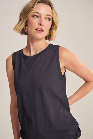 A woman with short blonde hair wears the TAURUS TANK TOP by Velvet by Graham & Spencer and gold hoop earrings, standing against a plain background.