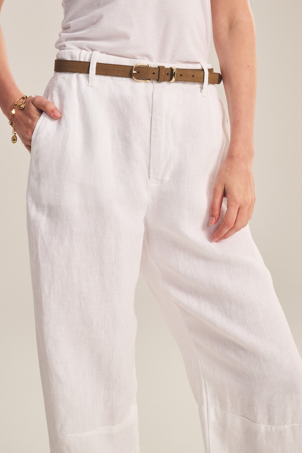 Person wearing a white shirt and Velvet by Graham & Spencer TAYLOR HEAVY LINEN PANT with a brown belt, left hand in pocket, and gold bracelet on right wrist.-41008421109953
