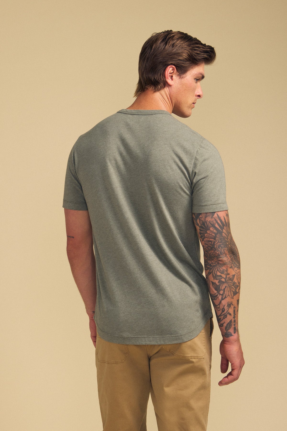 Man with his back to the camera, wearing the HARRIS TEE in grey by Velvet by Graham & Spencer and khaki pants, displays a tattoo sleeve on his left arm.-41702022447297