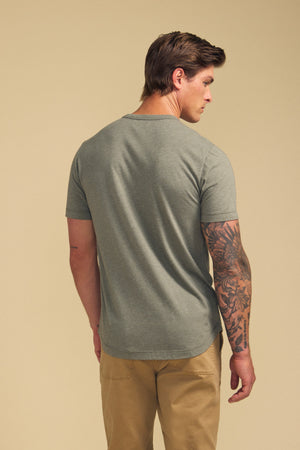 Man with his back to the camera, wearing the HARRIS TEE in grey by Velvet by Graham & Spencer and khaki pants, displays a tattoo sleeve on his left arm.